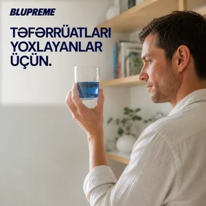Əlində mavi maye olan stəkan tutan şəxs