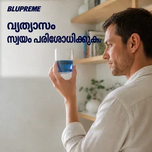 ഒരു ഗ്ലാസ് നീല ദ്രാവകം കൈവശം വച്ചിരിക്കുന്ന വ്യക്തി