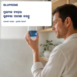 ଏକ ଗ୍ଲାସ୍ ନୀଳ ତରଳ ଧରିଥିବା ବ୍ୟକ୍ତି