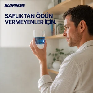 Elinde mavi sıvı dolu bardak tutan kişi